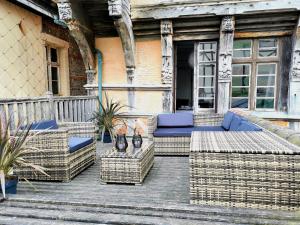 un porche con muebles de mimbre en una terraza de madera en Hotel La Résidence Manoir De La Salamandre, en Étretat