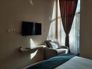 a bedroom with a tv and a chair and a window at Вила Bora Vista 1 in Tsigov Chark