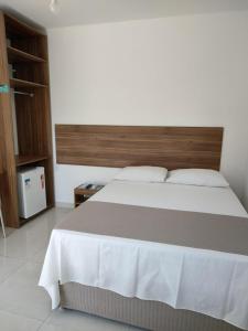 a bedroom with a large bed with a wooden headboard at Pousada Verçosa - Rota Ecológica dos Milagres in Passo de Camarajibe