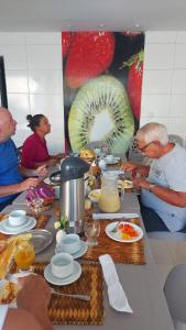 Pousada Verçosa - Rota Ecológica dos Milagres في Passo de Camarajibe: مجموعة من الناس يجلسون حول طاولة مع الطعام