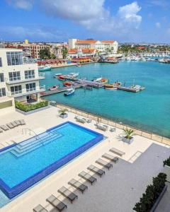 a large swimming pool next to a body of water at Stylish luxury condo, central location, ocean view, pool, gym in Oranjestad