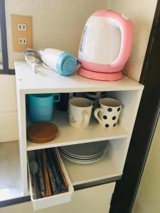 a kitchen shelf with dishes and a toaster on it at Garden House Ozasa - Vacation STAY 9178 in Fukuoka