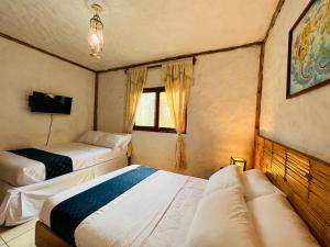 a bedroom with two beds and a tv and a window at Mamma Mía in Máncora