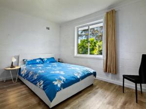 - une chambre avec un lit doté de draps bleus et une fenêtre dans l'établissement Marine house, à Narooma