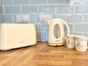 a toaster and two cups on a kitchen counter at The Home Stables in Southwick