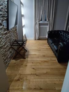 sala de estar con sofá negro y suelo de madera en B&B San Paolo Sweethome, en Parma