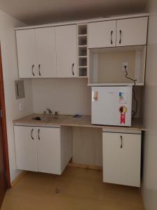 uma cozinha com armários brancos, um lavatório e um frigorífico em Flat Particular Hotel Saint Paul em Brasília