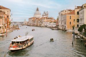 a tour boat on a canal in a city at Salute Palace powered by Sonder in Venice