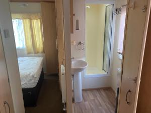 uma casa de banho com um lavatório, uma cama e um espelho. em Dunlin Dell at Thornwick Bay, Haven site em Flamborough