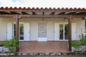 a patio with white doors and a wooden pergola at FarmBill in Markopoulo