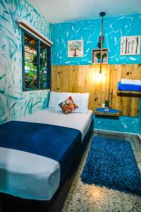 a bedroom with a large bed with blue walls at Hostal The Garden Lleras 10 in Medellín