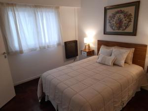 Un dormitorio con una cama grande y una ventana en Apartamento Esmeralda en Mar del Plata