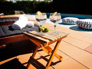 dos copas de vino en una mesa de madera junto a una piscina en Posada Santa Ana, en Suances