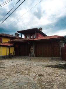 a red and yellow house with a building at Стаи за гости Бащино огнище in Koprivshtitsa