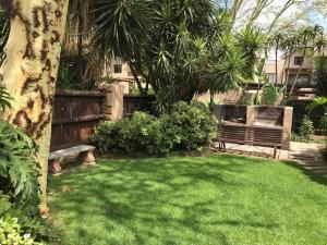 a yard with a park bench and a tree at Perfectly located beauty in secure Estate in Sandton