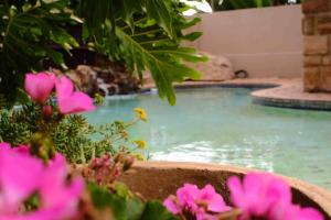 a swimming pool with pink flowers in a yard at Perfectly located beauty in secure Estate in Sandton