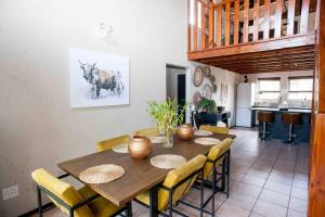 a dining room with a wooden table with yellow chairs at Perfectly located beauty in secure Estate in Sandton