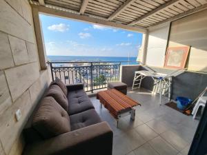 een woonkamer met een bank en uitzicht op de oceaan bij Sunset and sea view, wifi and more in Ashkelon