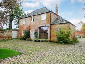 uma antiga casa de tijolos com uma entrada de pedra em The Coach House em Syston