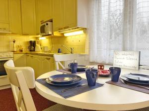 a kitchen with yellow cabinets and a white table with plates at Finnish house near the forest in Lappeenranta