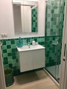 un bagno piastrellato verde con lavandino e doccia di Appartamento signorile, luminosissima vista mare a Fregene