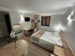 Una habitación de hotel con una cama y una mesa con escritorio. en Hotel Ijuí, en Ijuí