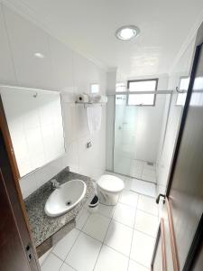 a white bathroom with a toilet and a sink at Hotel Ijuí in Ijuí