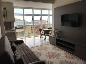 sala de estar con sofá y TV en Apartamento requintado com vista para o mar- Casagrande 202, en Bombinhas