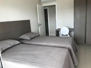 a bedroom with two beds and a chair in it at Apartamento requintado com vista para o mar- Casagrande 202 in Bombinhas