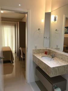 a bathroom with a sink and a mirror at Apartamento requintado com vista para o mar- Casagrande 202 in Bombinhas