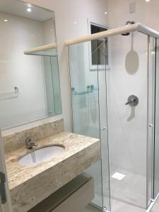 a bathroom with a sink and a glass shower at Apartamento requintado com vista para o mar- Casagrande 202 in Bombinhas