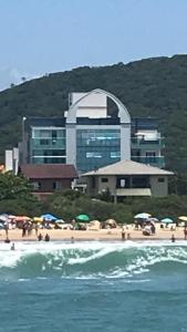 un grupo de personas en una playa con un edificio en Apartamento requintado com vista para o mar- Casagrande 202, en Bombinhas