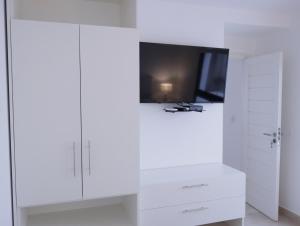 Habitación blanca con TV y armarios blancos. en 5C Departamento de dos ambientes, por escalera. en Mar del Plata