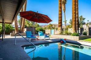 einen Pool mit 2 Stühlen und einem Sonnenschirm in der Unterkunft Siesta del Sol in Palm Springs