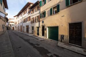 an empty street with buildings and a green garage at IBibiena - SUITE CECCO E MEA in Bibbiena