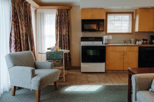a living room with a kitchen with a couch and chairs at Skaneateles Suites in Skaneateles