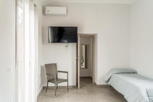 - une chambre avec un lit, une chaise et une télévision dans l'établissement Delia case vacanza, à Fiumefreddo di Sicilia