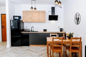 a kitchen with a wooden table and a black refrigerator at Mazurski Apartament in Szczytno