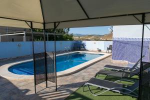 a swimming pool with an umbrella and chairs next to it at El Rincón De Resu in Los Baños