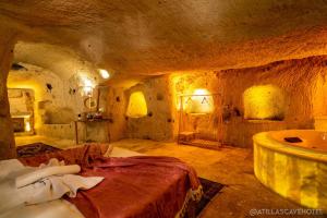 ein Schlafzimmer mit einem Bett und einer Badewanne in einer Höhle in der Unterkunft Atilla's Cave Hotel in Nevşehir