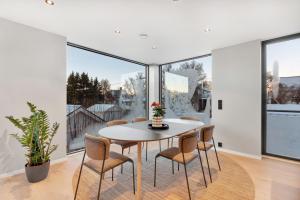 a dining room with a table and chairs and large windows at Osiris Home in Tromsø