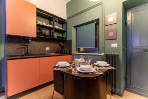 een keuken met oranje en groene muren en een tafel bij Rasella44, Green Apartment in Rome