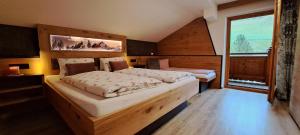 een slaapkamer met 2 bedden en een groot raam bij Appartements Alpenland - Ferienwohnungen in Auffach