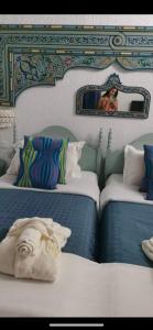 a room with two beds with a mirror and a woman taking a picture at Hotel Khella in Hammamet