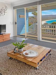 a coffee table in a living room with a view of the ocean at Bella Costa - Bay of Fires Beach House in Binalong Bay