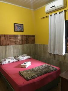 1 dormitorio con 1 cama con manta roja y ventana en Pousada Damasio, en Penha