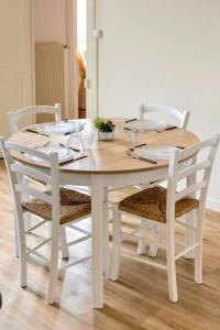 una mesa de comedor blanca con 4 sillas alrededor en Le Cocon d'Anna, en Dole