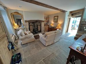 a living room with two white chairs and a fireplace at Brook House in Nunney