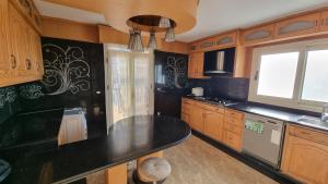 une cuisine avec des placards en bois et un comptoir noir dans l'établissement Sanstfano duplex apartment - families only, à Alexandrie