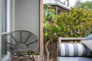 un fauteuil en rotin assis sur une terrasse couverte à côté d'une fenêtre dans l'établissement By The Seaside, à Mornington